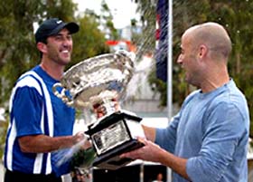 Andre Agassi of the USA holds the winner's trophy, as he is sprayed with champagne by his coach Darren Cahill