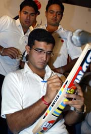 Indian captain Saurav Ganguly autographs a bat as team-mates Yuvraj Singh and Dinesh Monia look on 