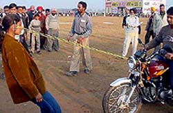 A girl pulling a motorcycle with its rider by her ears 