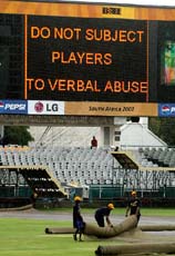 Groundskeepers cover up the field at Newlands Cricket Ground in Cape Town during a steady rain