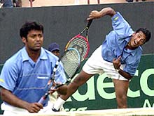 Mahesh Bhupathi serves as his doubles partner Leander Paes looks on
