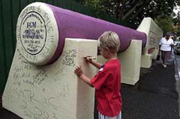 A young cricket fan signs a 16-meter-long fibre glass cricket bat