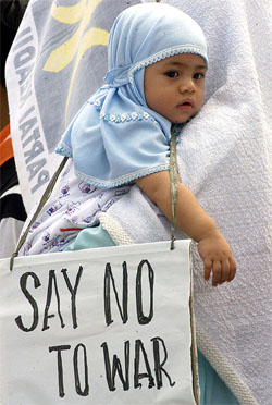 An Indonesian mother carrying her child attends an anti-war protest in front of the US Embassy