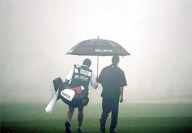 Tiger Woods walks in the fog with his caddie Steve Williams