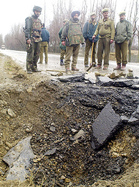 Paramilitary soldiers stand near a crater