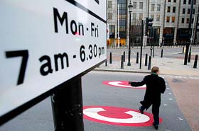 A man crosses the road over a "C" sign marking the start of the congestion charging zone in central London 
