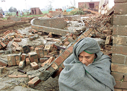 A man huddles besides his destroyed house near Lahore 