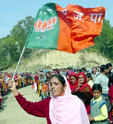 A woman holds aloft the BJP flag at a rally near Hamirpur 