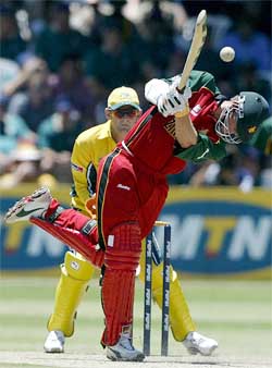 Zimbabwe's Andy Blignaut hits a six as Australia's wicketkeeper Adam Gilchrist looks on