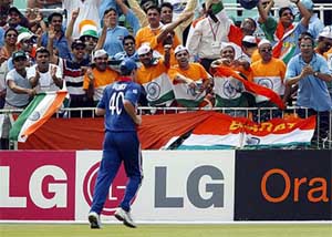 Indian fans point towards the ball as an England fielder runs to collect it 