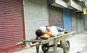 A daily wage earner takes a nap as traders observe a bandh 