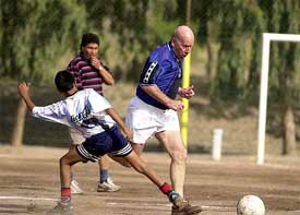 British soccer legend Bobby Charlton plays with children of a shantytown 