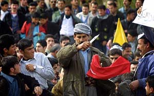 An Iraqi Kurd cuts a Turkish flag during a demonstration to protest possible Turkish intervention 