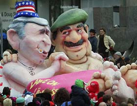 A carnival float carries paper figures of US President George W. Bush and Iraqi President Saddam Hussein sitting together in a bed