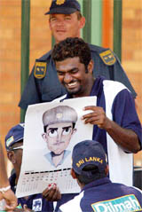 Sri Lanka's Muttiah Muralitharan laughs as he looks at a calendar containing a caricature of Indian captain Saurav Ganguly