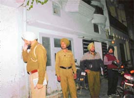 Police personnel wait outside the house of Ramesh Kumar