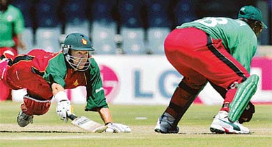 Zimbabwean batsman Andy Flower dives back to make his ground as Kenyan wicketkeeper Kennedy Otieno waits for the ball 