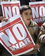 A Palestinian boy carries a "No War" poster during a demonstration in the West Bank city of Ramallah