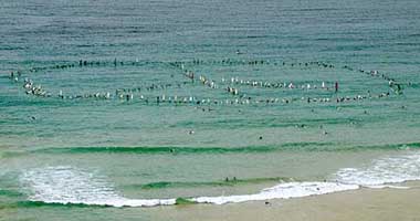 Surfers form a giant peace sign in the sea at the Queenscliff Beach