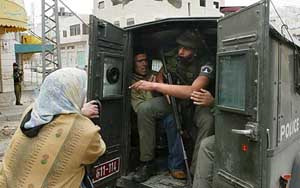 A Palestinian woman grabs the door of an Israeli military jeep after the arrest of her son 