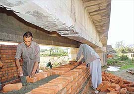 Labourers employed by the Marketing Board, Haryana, repair a vital bridge