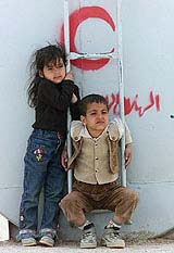 Young refugees from Iraq sit near a cistern with water