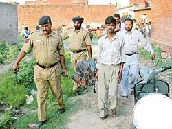 Policemen carry the body of Satish Kumar for a postmortem examination in Hallo Majra village on Tuesday.