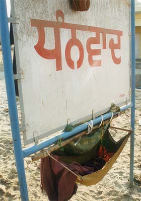 A child sleeps in a swing temporarily erected on a board put up for road signs