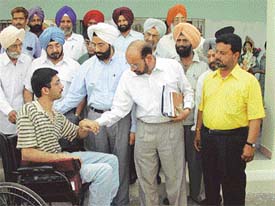 A physical challenge: Dr D. P. S. Sandhu, Director, Health Services, Punjab, and Capt Jaiya, Secretary, state unit of the Indian Red Cross Society, present a tricycle and hearing aids to a physically challenged person