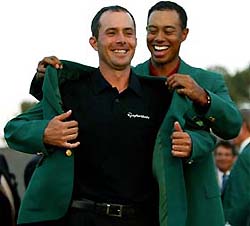 Canadian golfer Mike Weir receives his green jacket from former champion Tiger Woods