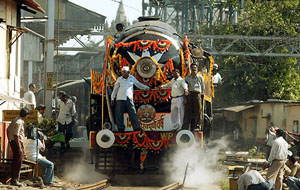A train pulled by two vintage steam engines makes its way through curious onlookers and photographers in Mumbai 