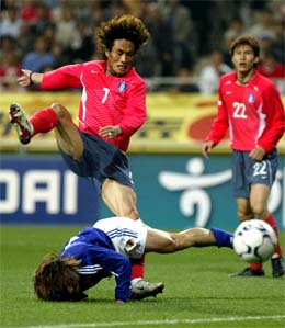 Japan's Daisuke Oku falls as he fights for the ball against South Korea's Kim Tae-young 