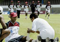 West Indies' Shivnarine Chanderpaul (C) has his injured knee bandaged prior to a team training session 