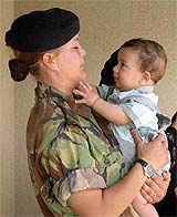 British Corporal Claire O'Connor holds an Iraqi baby at the opening of a primary school in the grounds of a British military base near Basra 