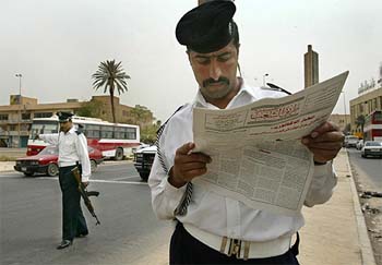 An Iraqi traffic policeman stops work to read a newspaper in a central Baghdad street on Sunday