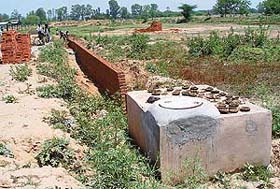 A boundary wall being raised by the land mafia on a piece of prime land earmarked for setting up of a sewerage treatment plant at Lohgarh village