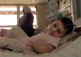 A three-year-old girl, Faruq Abdullah, suffering from a brain tumor, lies connected to a ventilator