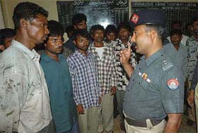 A Pakistani police officer talks to arrested Indian fishermen at a police station in Karachi