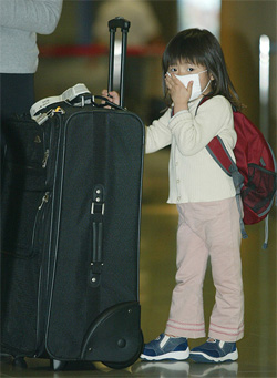 A girl arriving from Japan wears a mask to protect herself from the SARS virus