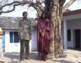 A woman psychiatric patient is hand-cuffed and tied to a tree