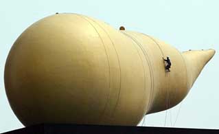 A man suspended by ropes cleans a giant monument