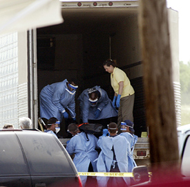 Authorities move dead bodies of illegal immigrants from the semi trailer they died in to another semi trailer for transportation to Austin, Texas