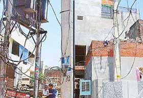 Loose overhead electricity wires hang precariously just at about human height in Mani Majra (left); and an electricity pole being taken into the boundary of the Sector 32-C rehabilitation colony (right).