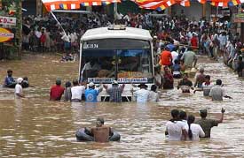 Townsfolk push a bus through floodwaters in Ratnapura