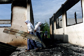 Students remove the ruins of a classroom at a school which was burned down overnight in the troubled Aceh province