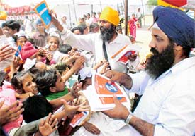 Members of the Delhi Sikh Gurdwara Management Committee distribute anti-drug literature among villagers
