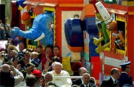 Pope John Paul II waves to pilgrims as he passes a wooden train