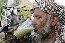 An elderly Pakistani slakes his thirst with a glass of iced sugarcane juice