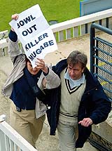 An anti-Mugabe demonstrator being escorted from the pitch during the opening day's play of the first Test match between England and Zimbabwe