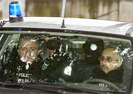 An unidentified suspected al-Qaeda member wearing a hood sits in a police car